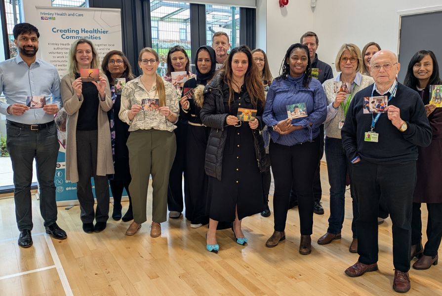 A group of men and women of diverse races each holding a photo facing the camera.